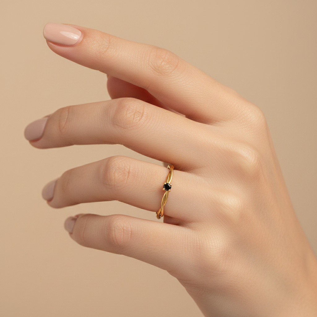Lifestyle photo of twisted multi-strand gold ring with black stone worn on hand