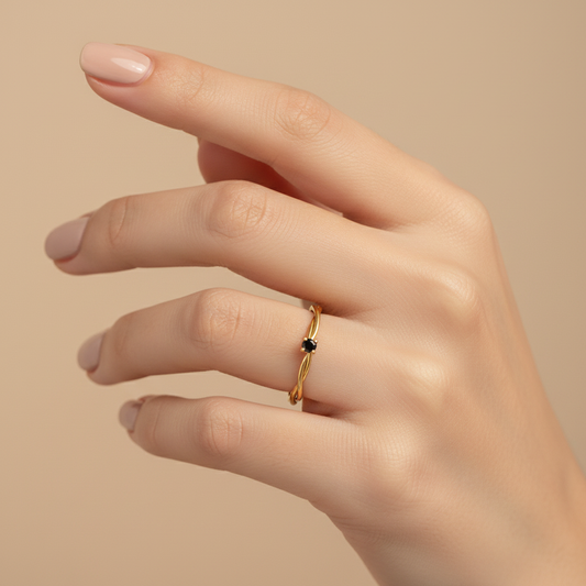 Lifestyle photo of twisted multi-strand gold ring with black stone worn on hand